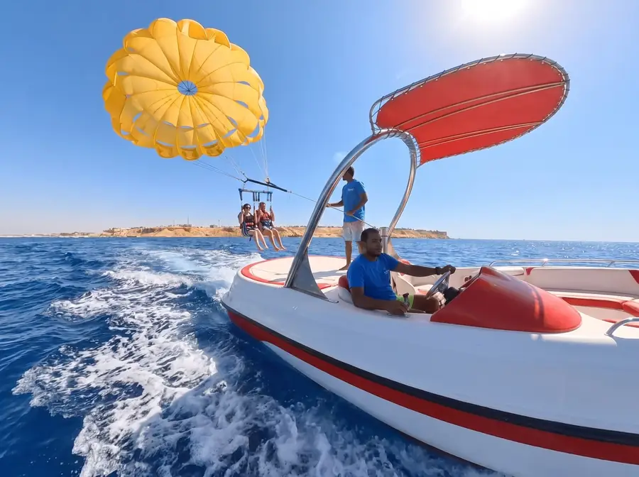 A parasail canopy climbing behind the speedboat over Naama Bay.