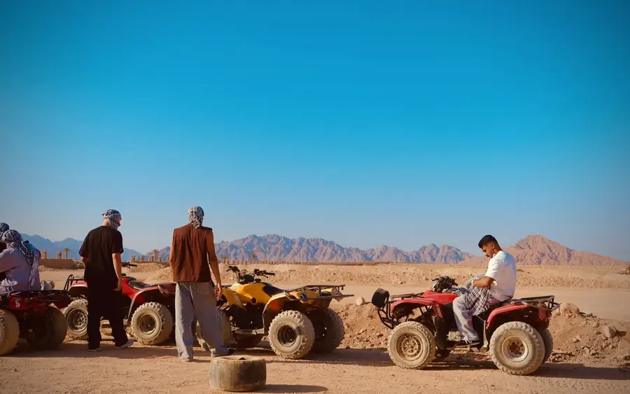 Quad bikes and riders stopped in the Sinai desert below the mountains.
