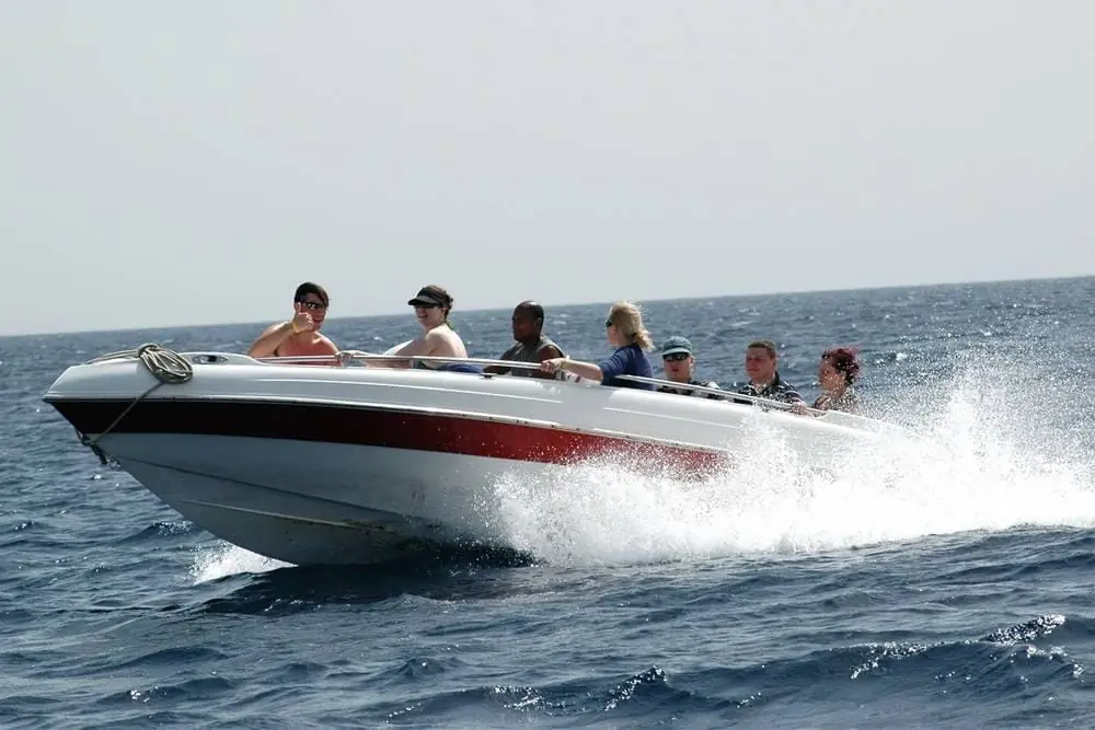 A speedboat with its passengers cutting through the spray