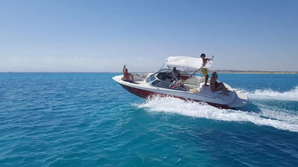 A guest standing and waving on a speedboat under way