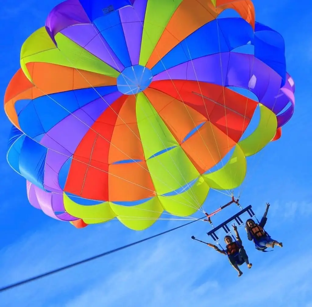 A rainbow parasail canopy with two riders below it