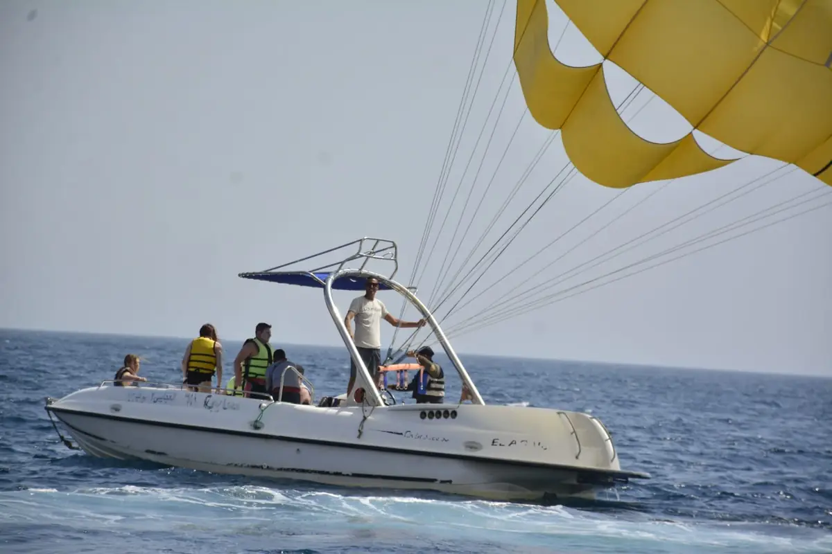 Guests in life jackets on the parasailing boat as the yellow canopy lifts