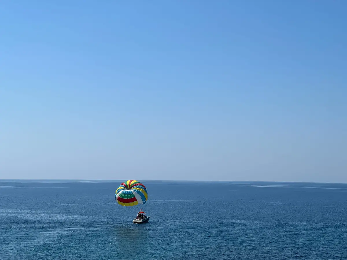 A parasail far out over a calm sea behind its tow boat