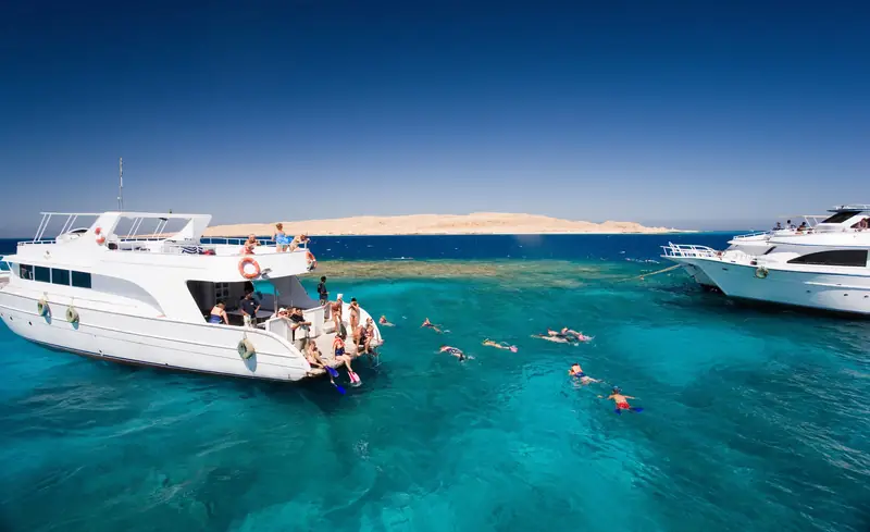 Day boats moored at the reef with snorkellers in the turquoise shallows