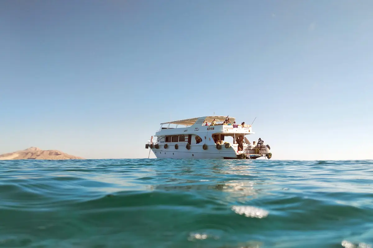 A day boat at anchor seen from the water, a desert headland on the horizon