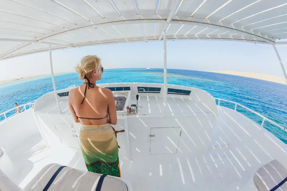 A guest on the shaded top deck looking out at the turquoise reef