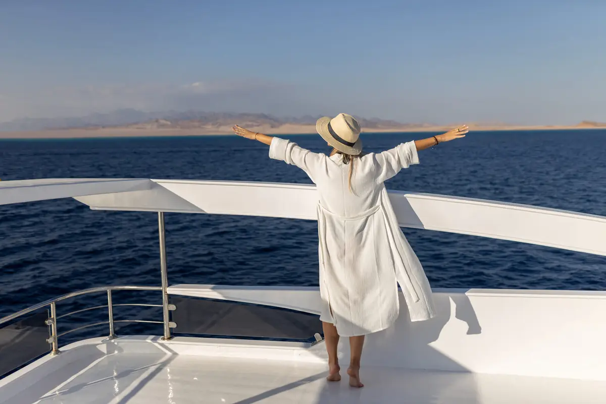 A guest at the bow with arms wide open, the Sinai mountains across the water