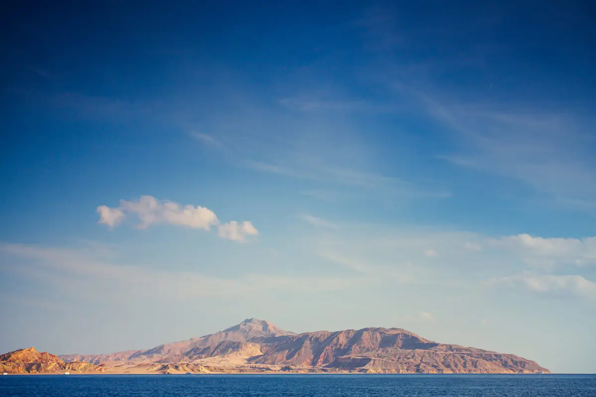 A mountainous island rising across the deep-blue Red Sea