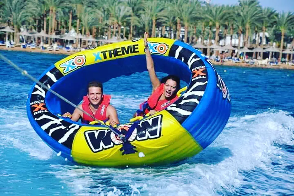 Two riders laughing inside a round towed tube