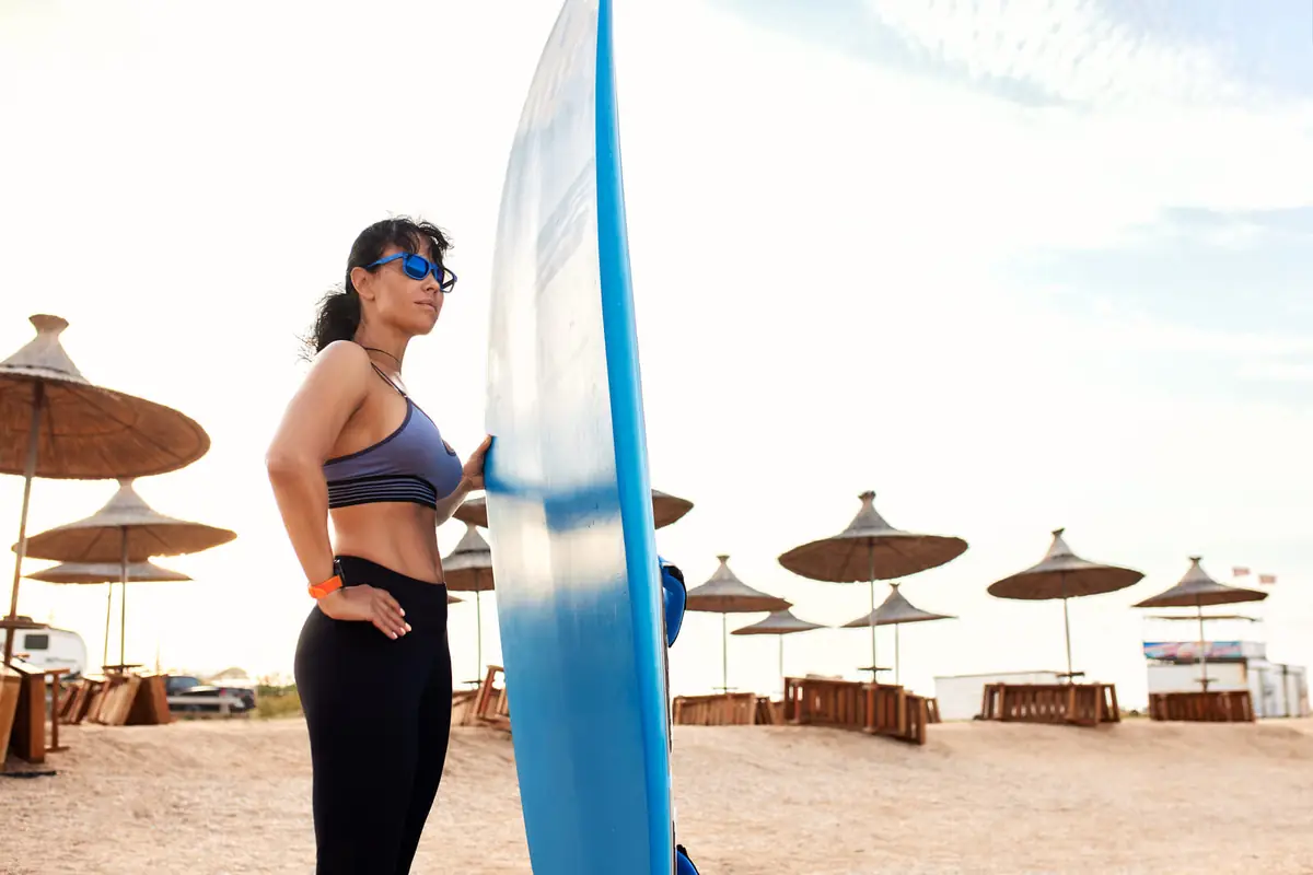 A paddler holding a stand-up paddle board on the beach