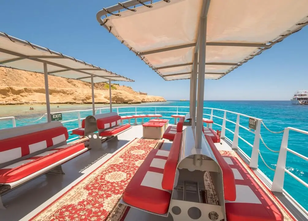 The shaded deck of the glass-bottom boat, with red benches and a patterned carpet
