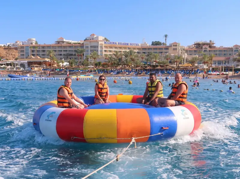 Four riders in a ringo tube being towed across the bay