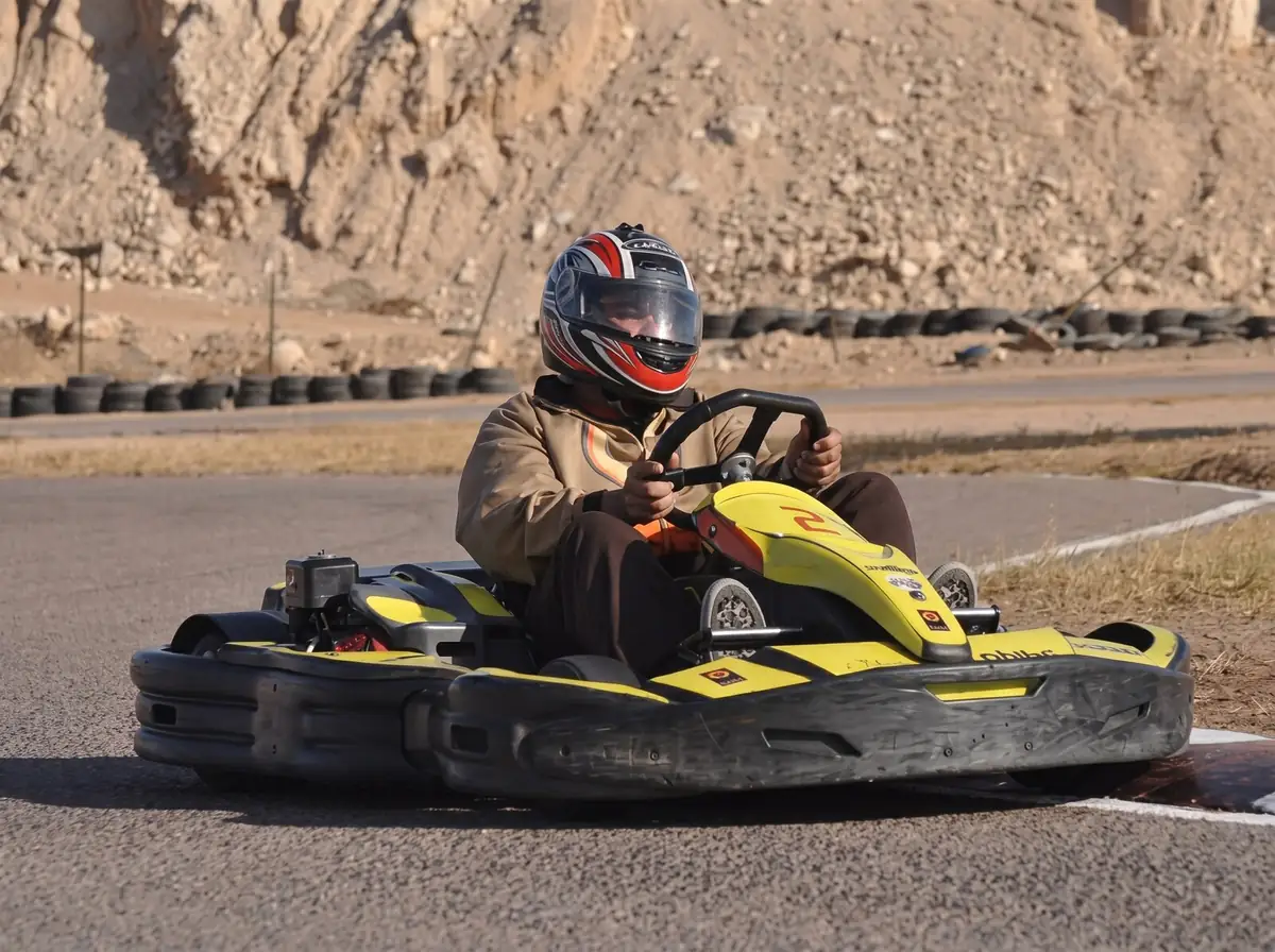 A driver in a helmet taking a corner in a go-kart
