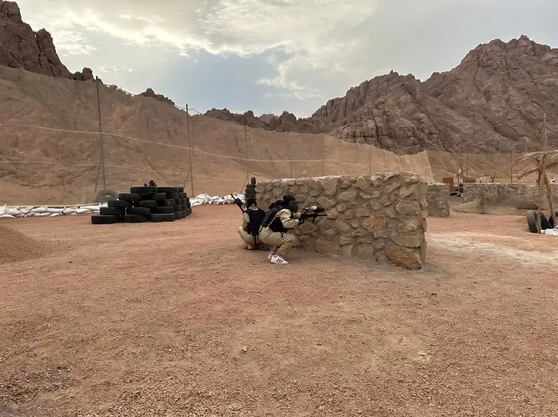 The paintball arena with tyre stacks and stone bunkers below the mountains