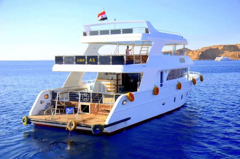 A white motor yacht flying the Egyptian flag at anchor on deep-blue water
