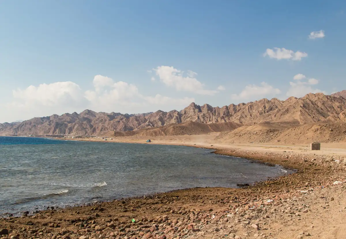 A quiet bay and its beach in front of a jagged desert mountain range