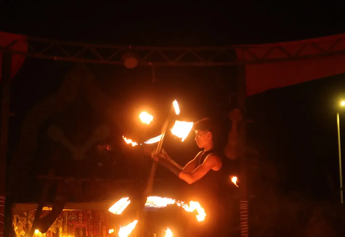A fire performer working the ring at a desert camp evening.